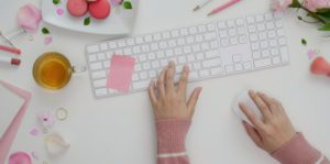 Keyboard on a desk with hands resting near it.