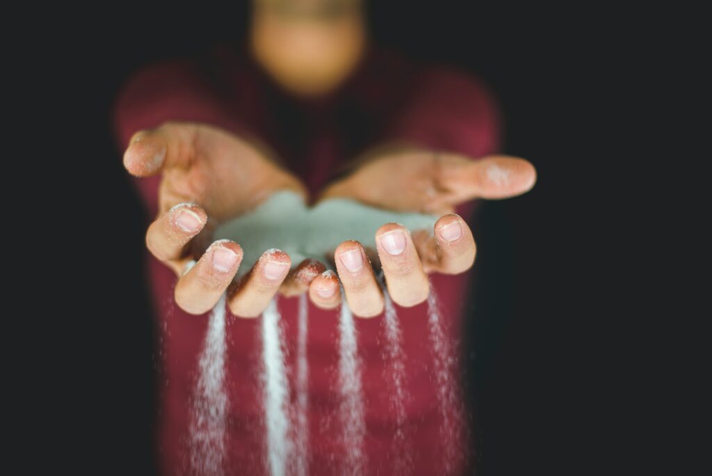 Two hands holding sand while it falls between the fingers.