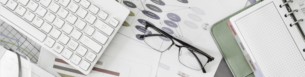 image of paperwork, glasses, and keyboard on an office desk.