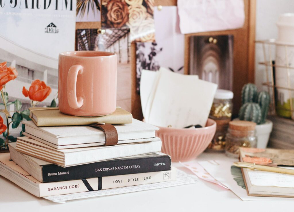 Desk supplies stacked on a desk with a coffee mug on top.